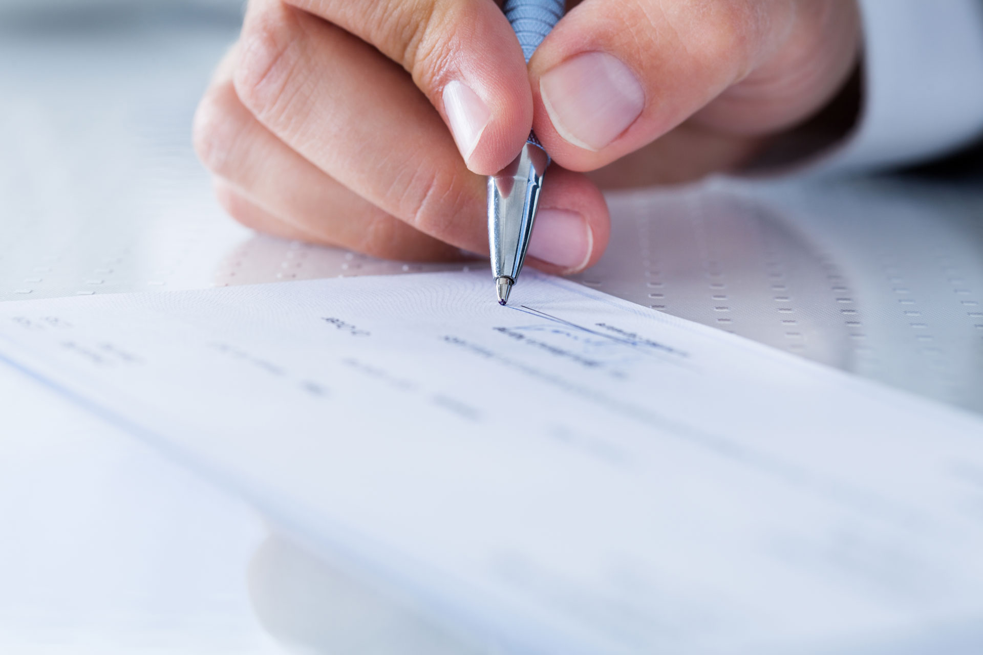 a person holding a pen over a piece of paper.